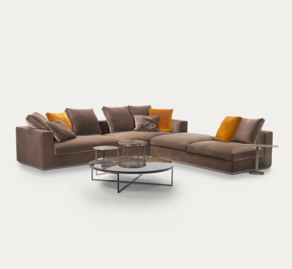 L-shaped velvet sectional sofa in warm taupe with mustard yellow cushions and glass coffee table
